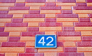 Number 42, forty-two, blue plate ona red brick wall pattern background.