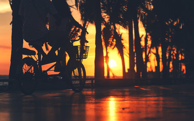 Couple ride bike on the road near the beach with sunset.
