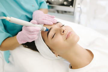 Close-up of woman getting facial hydro microdermabrasion peeling treatment. Female at cosmetic...