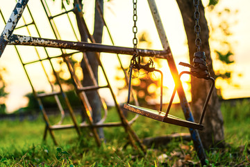 Broken chain swing in playground and light of sunset.