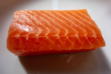 白い皿の上の生のサーモンの切り身