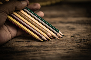 Arrangement of colored pencils on a dark brown wooden table. Cinematic concept to keep on being creative and a way to motivate children to continue their education.
