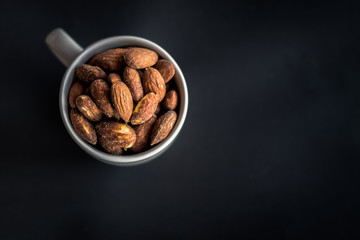 Closeup Salt Roasted Almond in a white cup on black background.