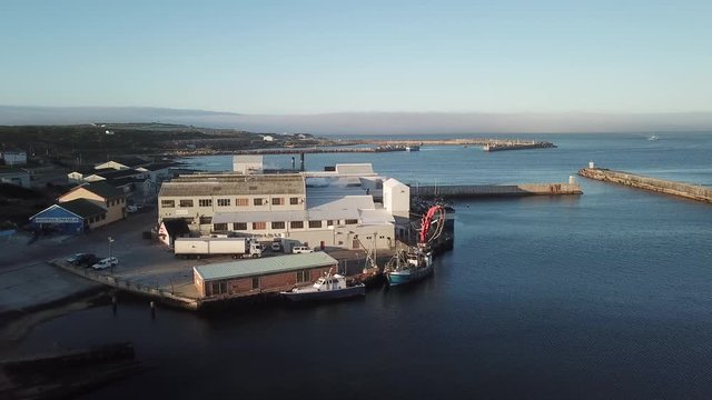 4K summer sunny morning aerial drone video of commercial harbour piers with vessels boats, fishing factory, town panorama, Indian Ocean coast town Gans Bay, Garden Route, Western Cape, South Africa