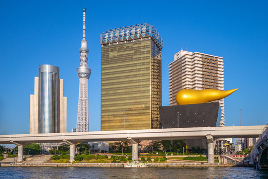 Tokyo, Japan - June 13, 2019: Asahi Beer Hall, designed by French designer Philippe Starck and was completed in 1989, on bank of Sumida River with tokyo skytree tower