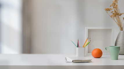 Close up view of  workspace with copy space, stationery, coffee cup, and decorations on white table with blurred background