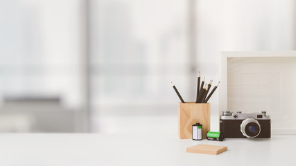 Cropped shot of workspace with copy space, camera, stationery, mock up frame, and tree pot on white...