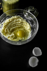 Homemade cakes, pastry and pie dough made from sugar, butter and raw egg. Eggshell on a black background. Open aperture