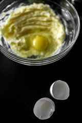 Homemade cakes, pastry and pie dough made from sugar, butter and raw egg. Eggshell on a black background. Open aperture