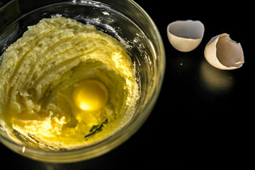 Homemade cakes, pastry and pie dough made from sugar, butter and raw egg. Eggshell on a black background. Open aperture