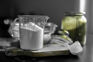 Ingredients for home baking: cookies, bread, cake. Flour, sugar, and eggs are on the black table. Baking dishes.