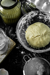Ingredients for home baking: cookies, bread, cake. Flour, sugar, and eggs are on the black table. Baking dishes.