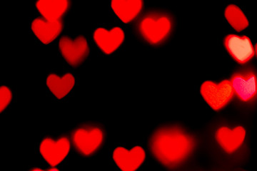 Fototapeta na wymiar Black background with bright red warm heart shaped bokeh lights. Holiday, Valentines Day background. Ideal to layer with any design. Horizontal