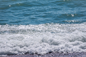 Sea water with foam on a pebble beach.