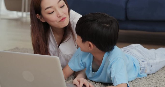 Mother and son using computer together at home with happy emotion.  Family, Technology and Lifestyle concept.