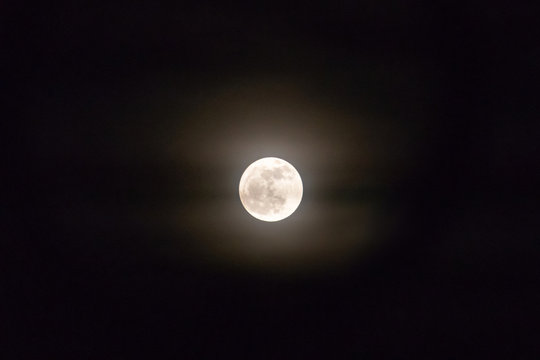 Full moon shining glowing light the night sky.