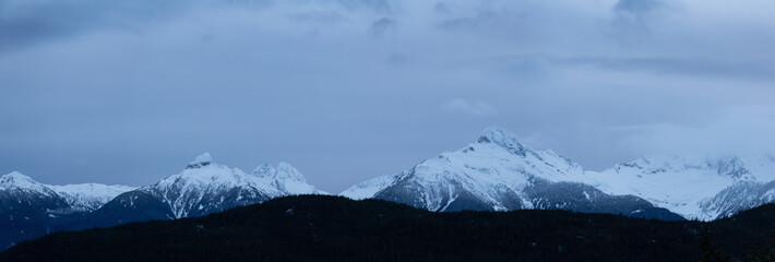 Fototapeta na wymiar Striking and Dramatic Panoramic Canadian Landscape View of the Mountain Peaks during a cloudy sunset. Taken in Tantalus Lookout near Squamish and Whistler, North of Vancouver, BC, Canada.