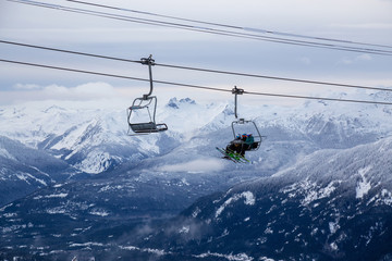 Obraz premium Whistler, British Columbia, Canada. People going up the mountain on a Chairlift during a vibrant and cloudy winter day.
