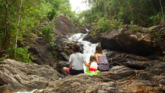 Family mom dad daughter sit and enjoy waterfall view