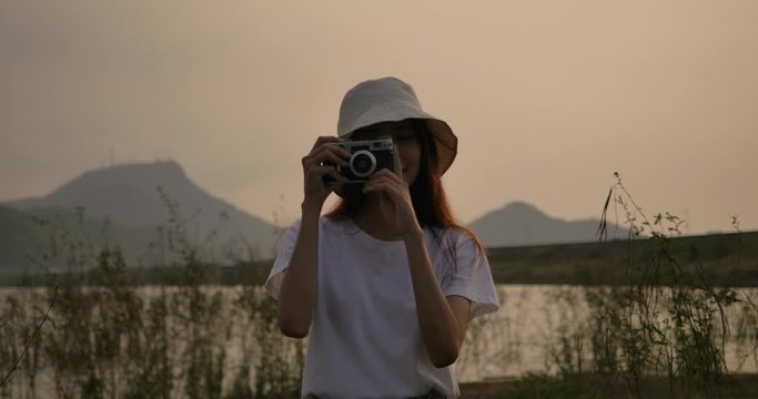 Super Slow motion C4K camera, Hipster young asian woman take a photo with film camera in the forest mountain river lake at sunset, Happy travel nature outdoors, Beauty girl travel people lifestyle