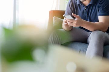 using cell phone.hand holding texting message on screen mobile chatting friend ,search internet information sitting on sofa in office.technology device contact communication connecting people concept