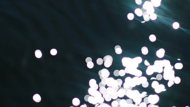 Bokeh sun glare reflected in water surface. Sunrays flickering in water stream. The shimmering small sea waves in sun. Abstract blurry out of focus bokeh background imagery.