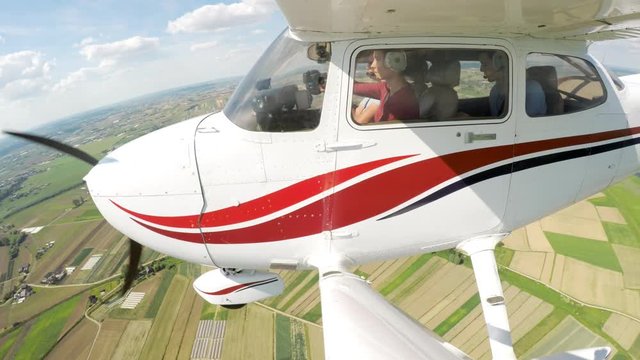 Young woman piloting a small private airplane beginning descent to approach cabin outside view