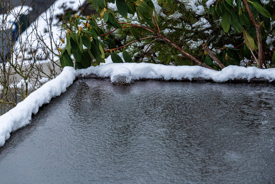 Flat Carport Roof Covered In Snow, Slush, Ice, And Water, With Clogged Downspout Drain