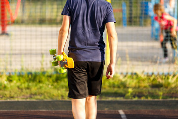 Close up legs in blue sneakers riding on yellow skateboard in motion. Active urban lifestyle of youth, training, hobby, activity concept. Active outdoor sport for kids. Child skateboarding.
