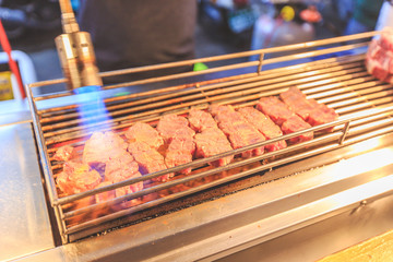 Wagyu beef steak cooking. Grilled beef on charcoal stove and torch burn. Barbecue wagyu steak Japanese Style. Saikoro Steak. Asian street food night market. Regional Food
