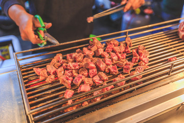 Beef Steak Dice Cooking. Grilled beef on charcoal stove and cutting. Diced Beef Steak Japanese Style. Saikoro Steak. Asian street food night market. Regional Food