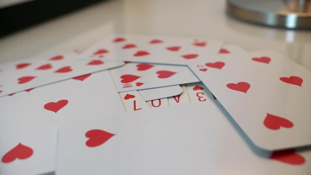 Smooth dolly in on playing cards reading LOVE, conceptual