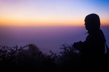 Silhouette of young photographer on the top of montain,looking out.