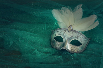 Photo of elegant and delicate white Venetian mask over mint chiffon background