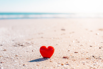 Fototapeta premium Romantic symbol of red heart on the sand beach