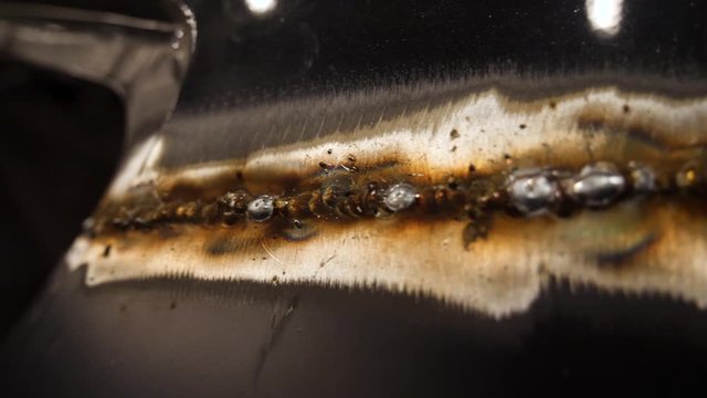 Jagged weld and slag on the side of a car before it is ground down to a smooth finish