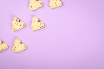 Flax seed cookies on purple background composition, heart shape.