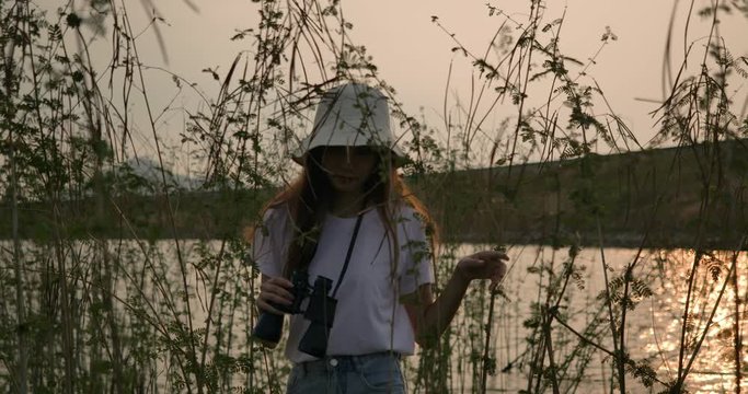 Traveler asian woman with binoculars adventure in the forest mountain river lake at sunset, happy travel get the atmosphere nature outdoors. Super slow motion C4K Cinematic camera footage