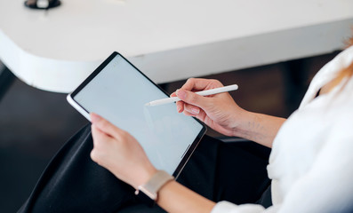 Cropped shot of female hand writing on tablet screen with stylus pen, blank screen for graphic...
