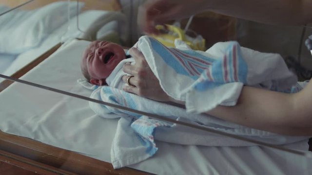 Crying Newborn Baby in Hospital Room Swaddled and Picked Up