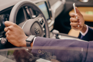 Close up of a man holding car's steering wheel.