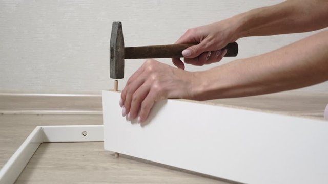 A woman collects boxes from chipboard with a hammer
