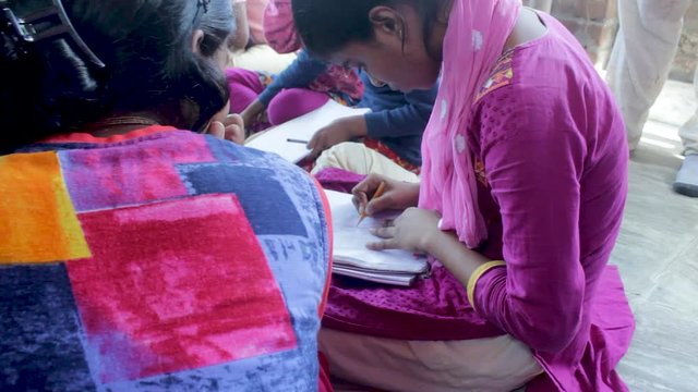 Indian girl student drawing in a sketchbook, seen from the side