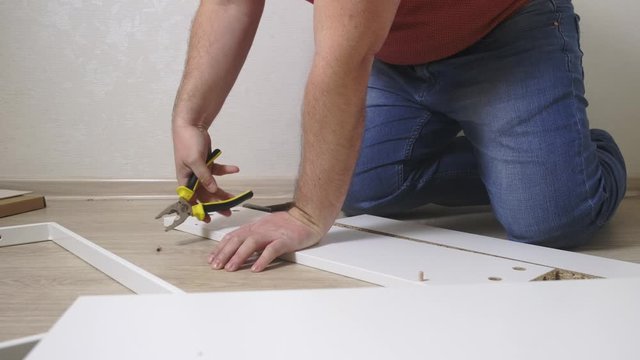 Man collects boxes from chipboard with a screwdriver