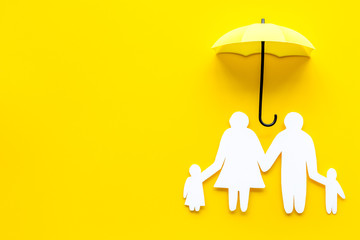 Live insurance concept. Family silhouette protected by umbrella on yellow background top-down copy...