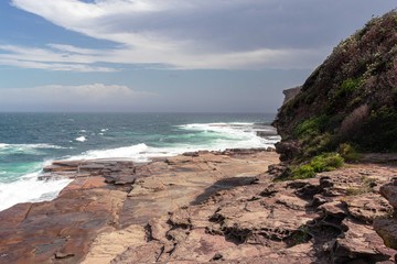 lookout beach with rocks, mountains and lots of vegetation around. blue sky blue-green sea