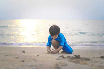A boy is playing sand and swimming with his brother on the beach.