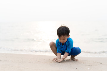 A boy is playing sand and swimming with his brother on the beach.