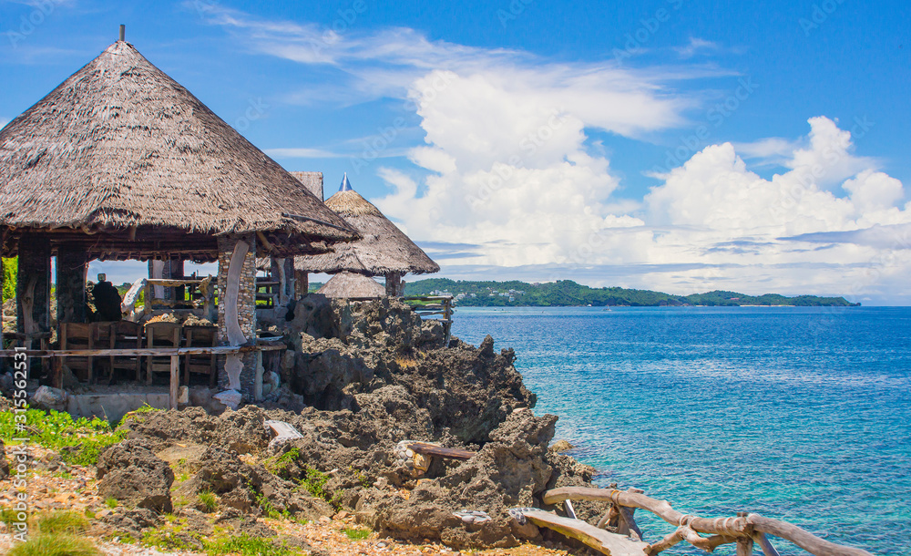 Wall mural gazebos with thatched roof on the shore of the blue sea. cloudy sky and beautiful sea