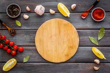 Mockup for menu. Cutting board near spices and vegetables on dark wooden background top-down